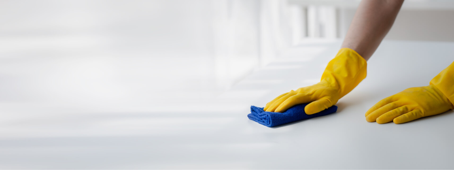 hero image of someone cleaning a surface with yellow gloves and blue cleaning cloth